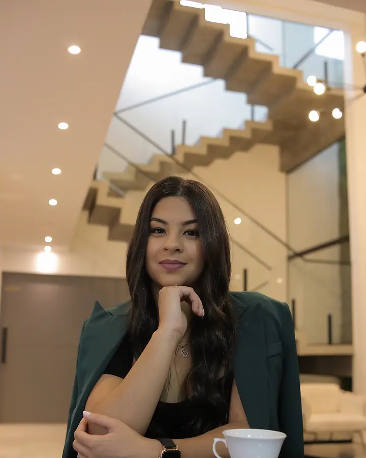 Dra. Akemy Rande de Sousa, de blazer verde, sentada à mesa, com a mão no queixo