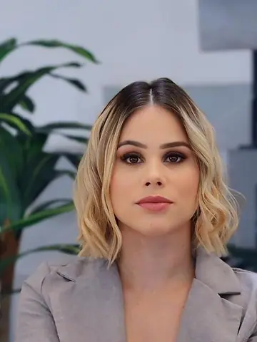 Dra. Letícia Moreira Amora, de terninho cinza, com os braços apoiados no joelho